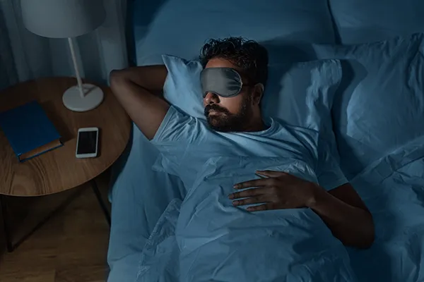 Comfortable man wearing an eyemask and sleeping in bed after visit to Sleep Apnea Solutions of Cincinnati in Cincinnati, OH