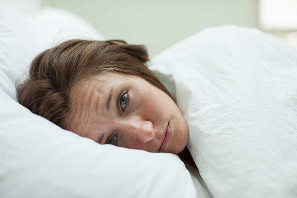 Tired woman laying in bed unable to sleep